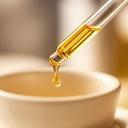 Goldfarbenes Serum in einer Glaspipette neben einer cremefarbenen Keramikschale